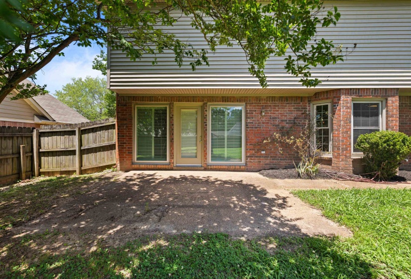 Private backyard featuring a concrete patio, wood privacy fencing, and a brick exterior facade