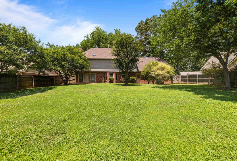 Expansive backyard featuring a lush lawn, mature trees, and privacy fencing