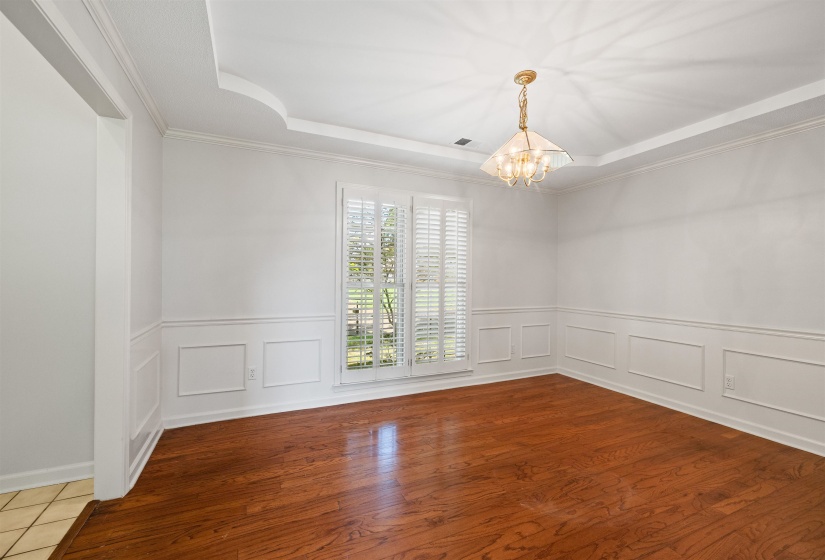 Formal room featuring wood-finish flooring, wainscoting, and crown molding