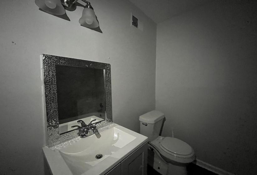 Powder room featuring a vanity with an integrated sink, a decorative framed mirror, and a wall-mounted light fixture