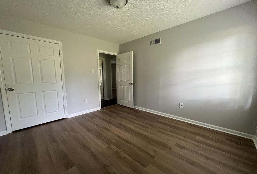 Interior room featuring wood-finish flooring, light gray walls, white baseboards, and a semi-flush mount ceiling light fixture