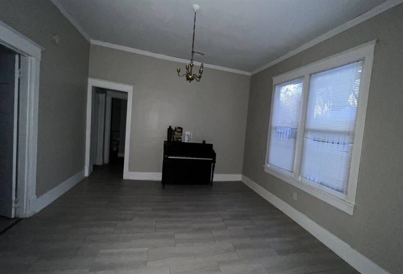 Spacious room featuring light gray walls, white baseboards, and wood-finish flooring