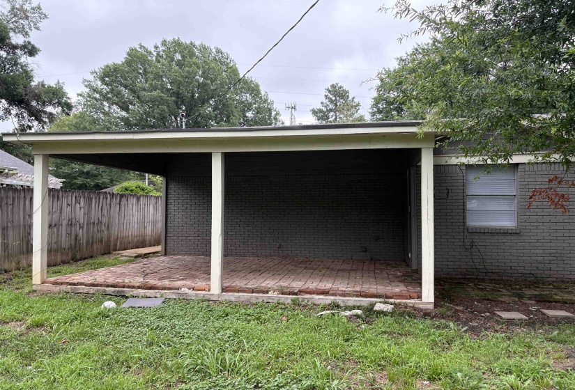 Covered brick patio featuring a gray brick exterior and a fenced perimeter