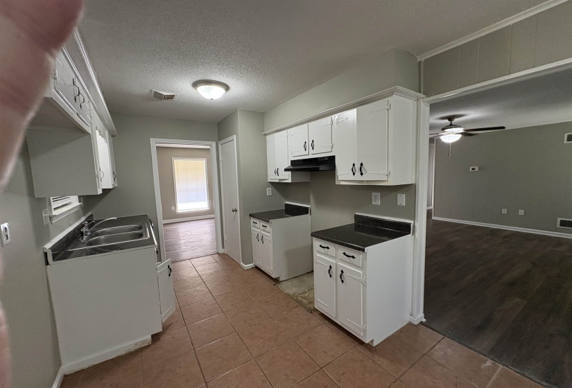 Kitchen featuring white cabinetry, dark countertops, a double basin sink, and tile flooring