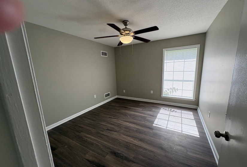 Room featuring wood-finish flooring, a ceiling fan with light fixture, a window with horizontal blinds, and baseboard trim