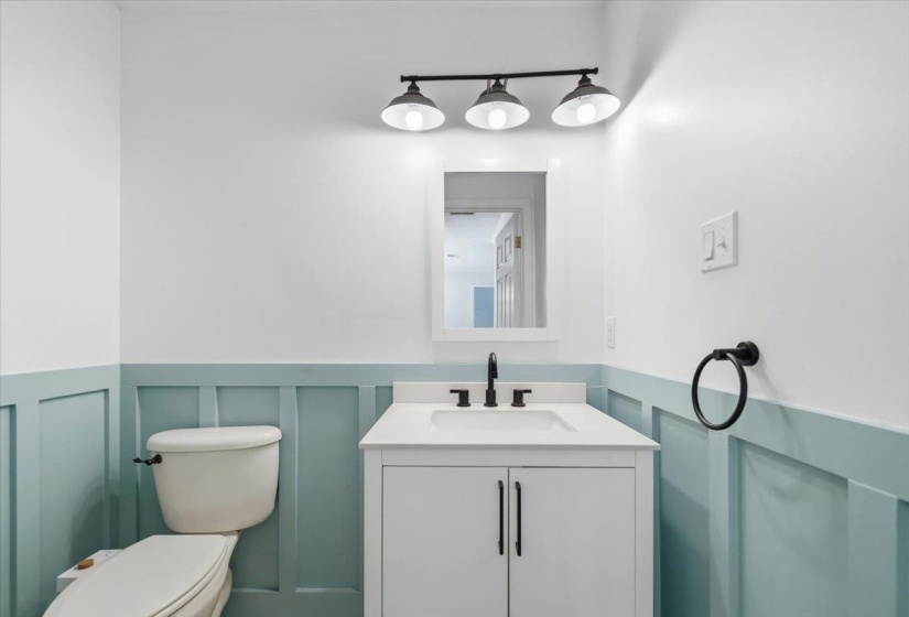 Bathroom featuring a white vanity with an integrated sink, matte black faucet, and a wall-mounted mirror