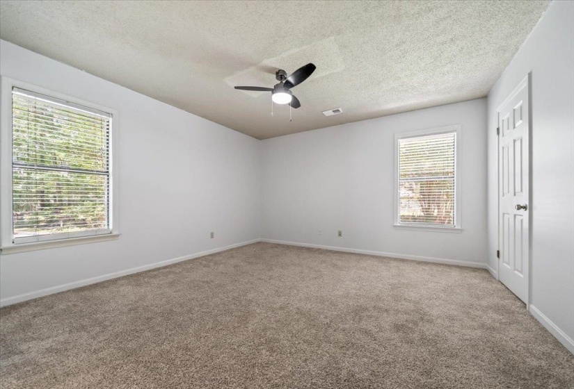 Spacious room featuring neutral carpeting, white walls, and two large windows with blinds