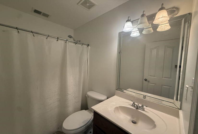 Bathroom featuring a vanity with a white countertop and integrated sink, a large wall-mounted mirror, brushed nickel faucet, and a shower with a white curtain