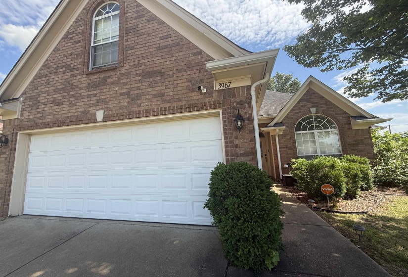 Brick exterior featuring a two-car garage with white panel doors, arched windows, and a covered entryway