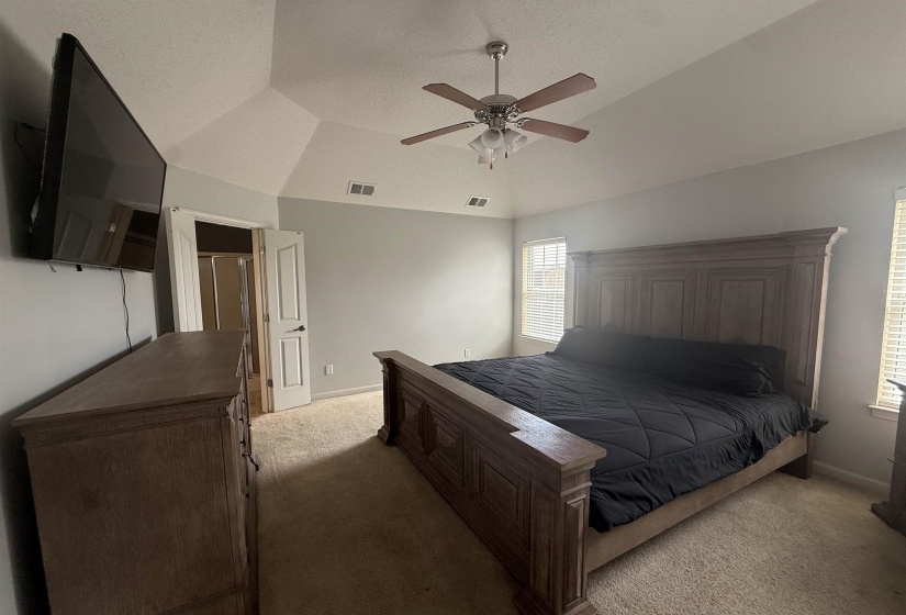 Spacious room with a vaulted ceiling, ceiling fan, and carpeted flooring