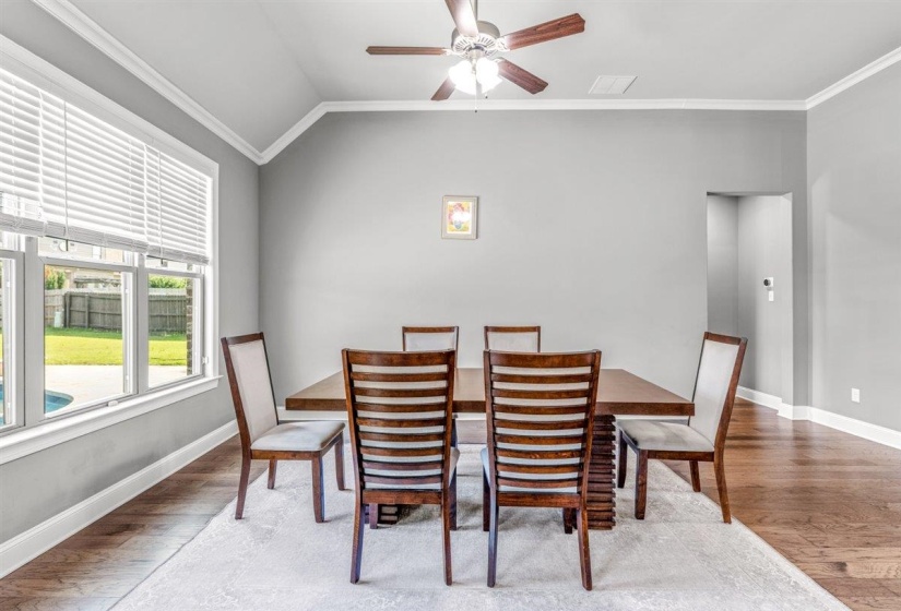 Spacious room featuring vaulted ceilings, wood-finish flooring, a contemporary ceiling fan, and large windows overlooking the backyard pool area