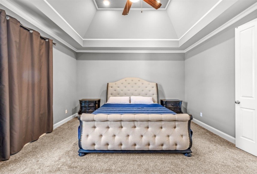 Carpeted room featuring a tray ceiling with crown molding, recessed lighting, and a ceiling fan