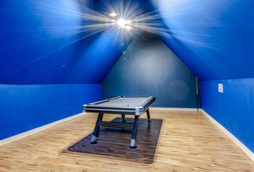 Versatile bonus room featuring wood-finish flooring, a built-in air vent, and sloped ceilings with a vibrant blue finish