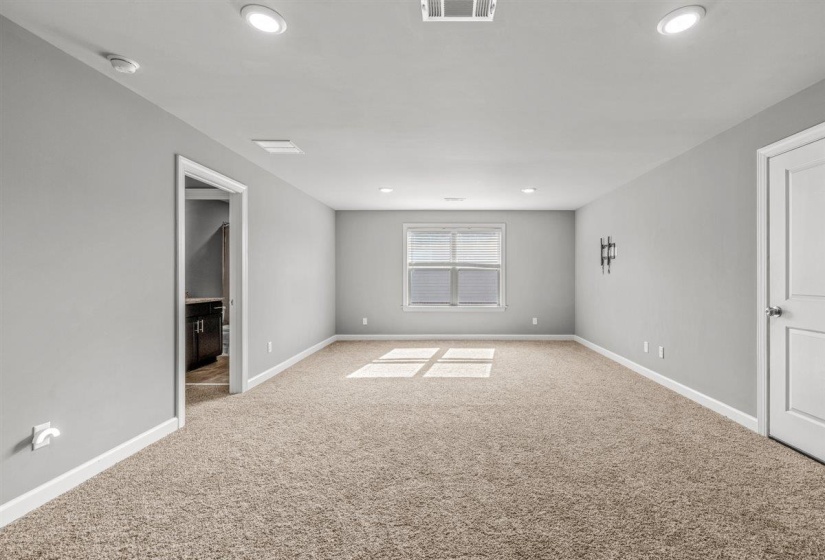 Spacious room featuring neutral carpeting, light gray wall paint, and white trim