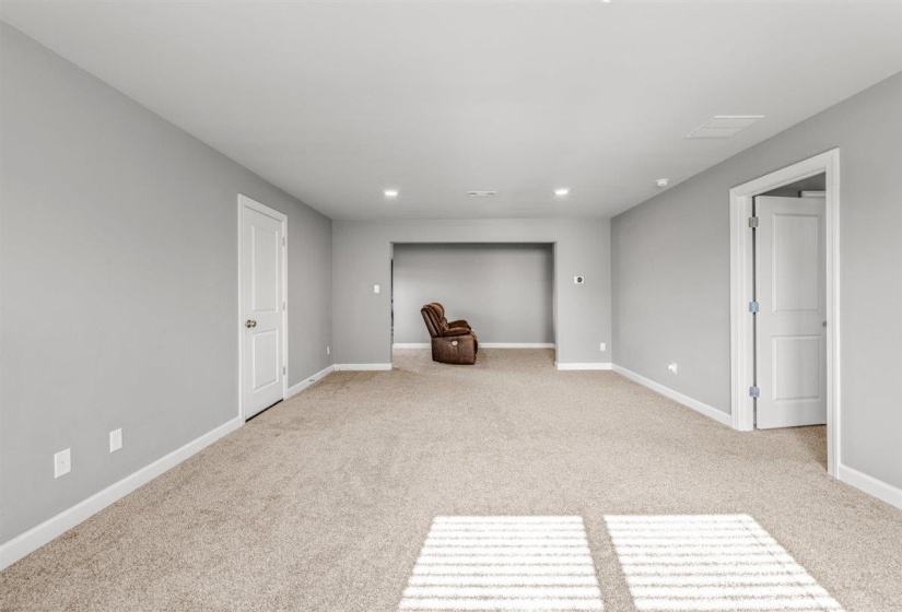 Open-concept interior featuring light gray walls, plush carpet flooring, recessed lighting, and white trim