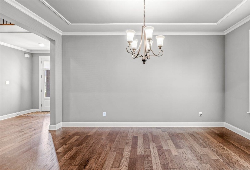 Room featuring wood-finish flooring, a decorative chandelier, and crown molding