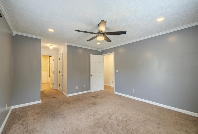 Spacious room featuring neutral carpeting, a ceiling fan with integrated lighting, recessed ceiling lights, and crown molding