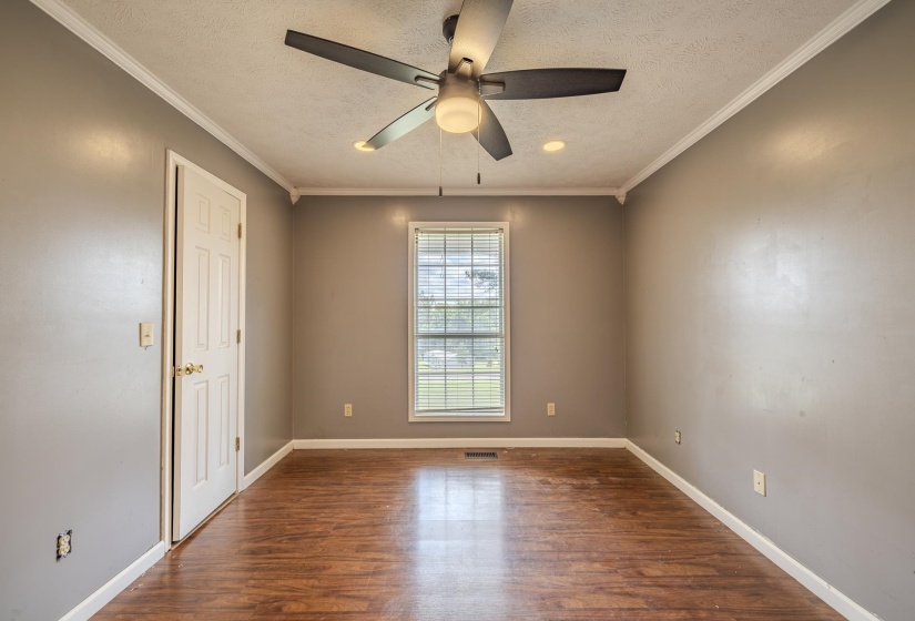 Room featuring wood-finish flooring, a window with horizontal blinds, neutral wall tones, and a ceiling fan with integrated lighting