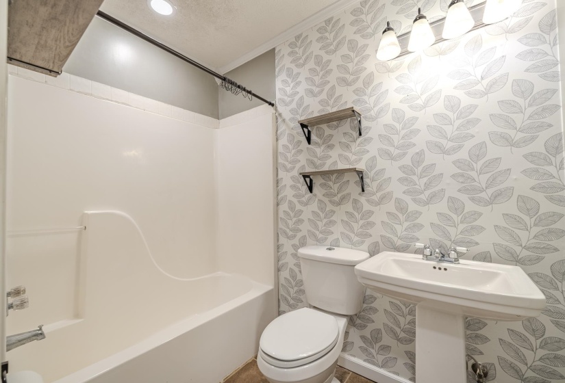 Bathroom featuring a white pedestal sink, toilet, and a white bathtub with shower
