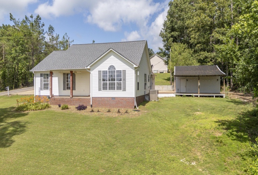 White siding home featuring a front porch with wooden columns, a curved arch window, and gray exterior shutters