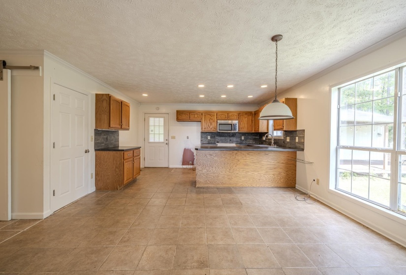 Open-concept kitchen and dining area featuring ceramic tile flooring, warm wood cabinetry, a built-in microwave, and recessed lighting