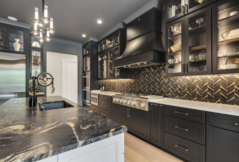 Spacious kitchen featuring a large island with a dark stone countertop, a built-in sink, and a unique faucet fixture