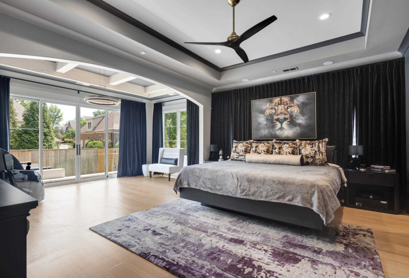 Spacious interior featuring light wood-finish flooring, a tray ceiling with recessed lighting, and a modern ceiling fan