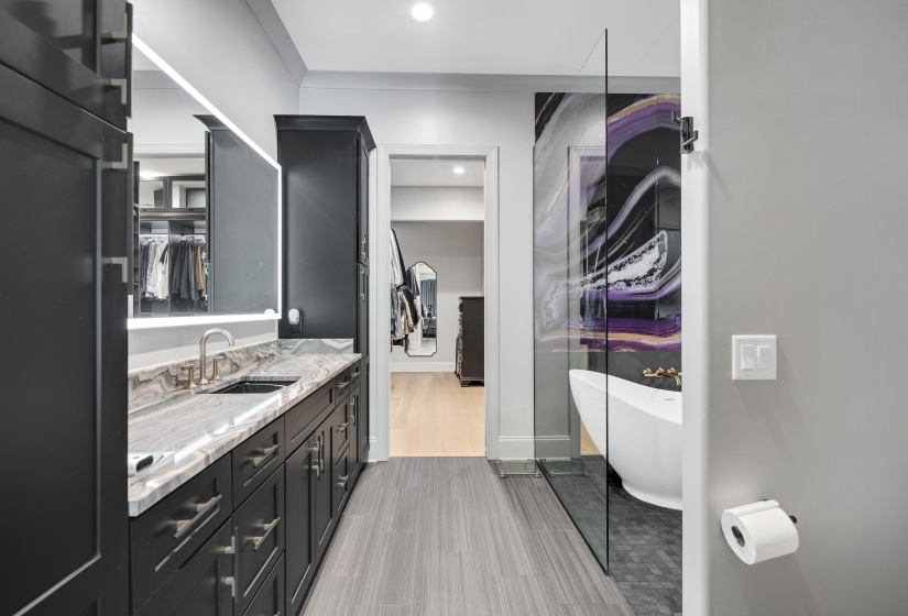Bathroom featuring a freestanding tub, glass-enclosed shower, dual vanity with undermount sinks, and a large illuminated mirror