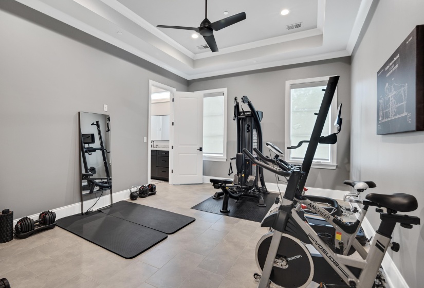 Spacious room featuring tray ceiling with recessed lighting and a ceiling fan, light gray walls, and tile flooring