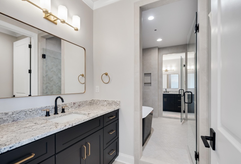 Bathroom featuring a dual vanity with granite-style countertop, matte black cabinetry, and gold-tone hardware