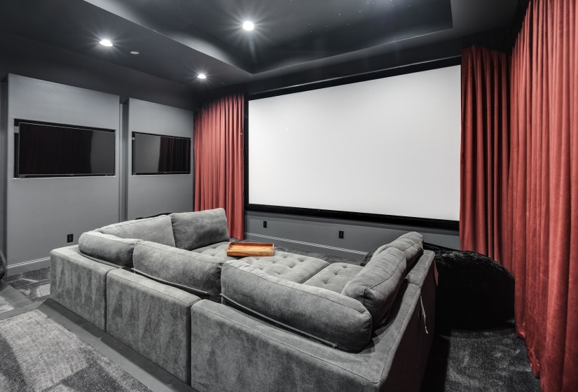 Dedicated media room featuring a large projection screen, recessed lighting, and wall-mounted display units