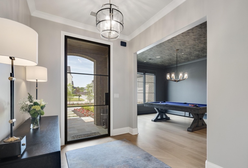 Entryway featuring a black-framed glass door, an ornate ceiling light fixture, and crown molding