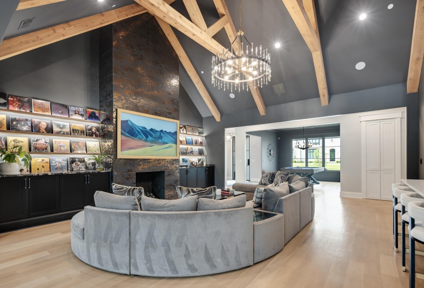 Vaulted ceiling with exposed wood beams, a prominent stone fireplace, and light wood-finish flooring