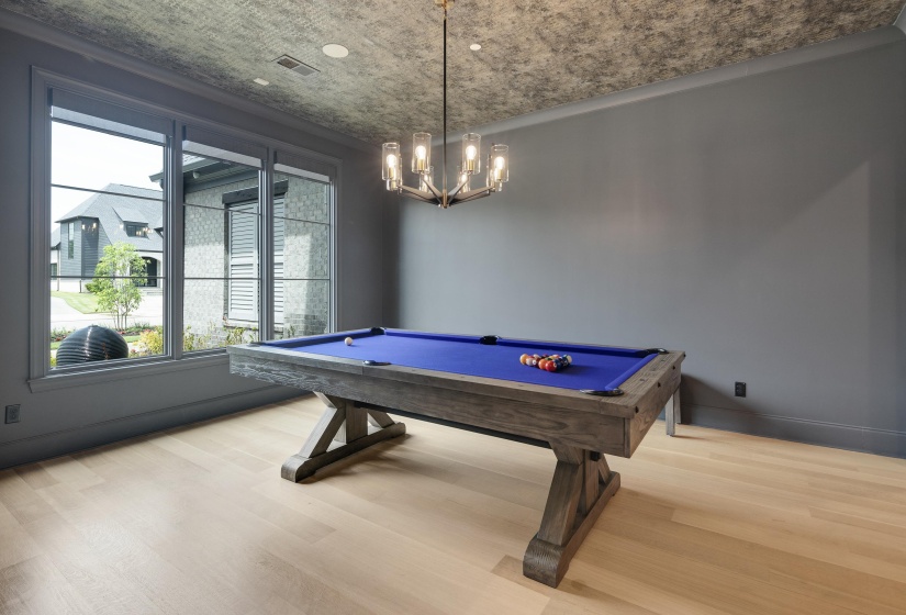 Spacious room featuring light wood-finish flooring, a textured ceiling, and a large multi-pane window