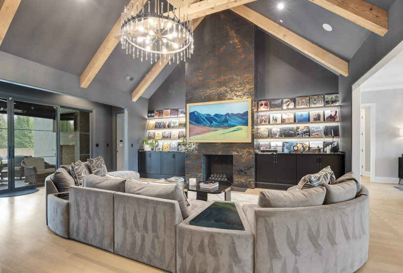 Vaulted ceilings with exposed wood beams define this living area, featuring a decorative fireplace with a textured surround