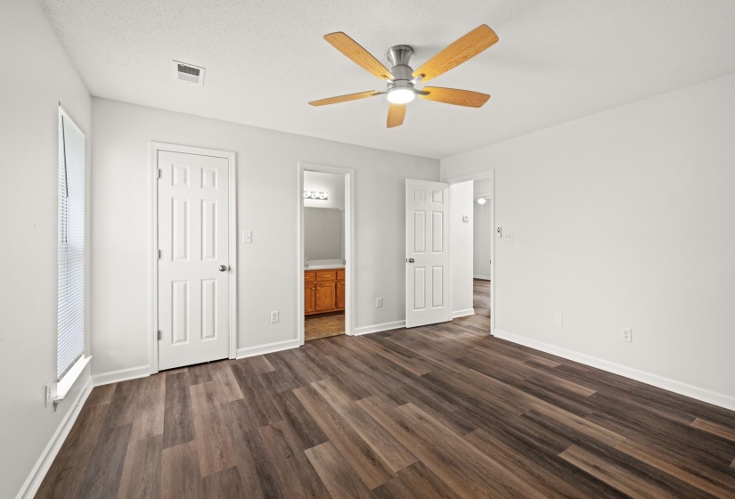 Spacious room featuring wood-finish flooring, white walls, and a ceiling fan with light fixture