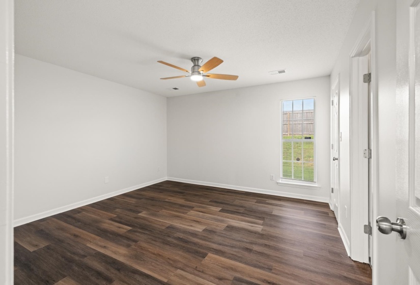 Bright room featuring wood-finish flooring, white walls, and a ceiling fan with light