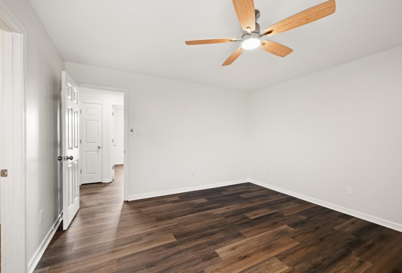 Spacious room featuring wood-finish flooring, light gray walls, and a contemporary ceiling fan with integrated lighting