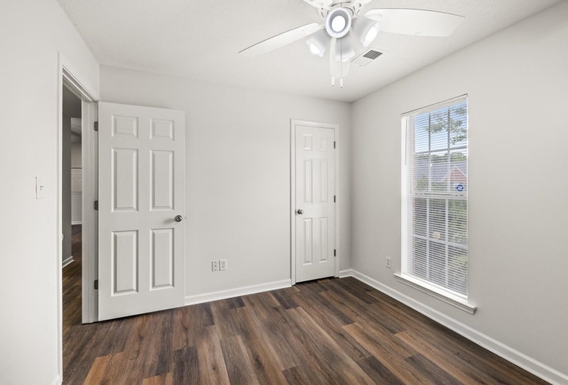 Room featuring wood-finish flooring, white walls, and a multi-pane window with blinds