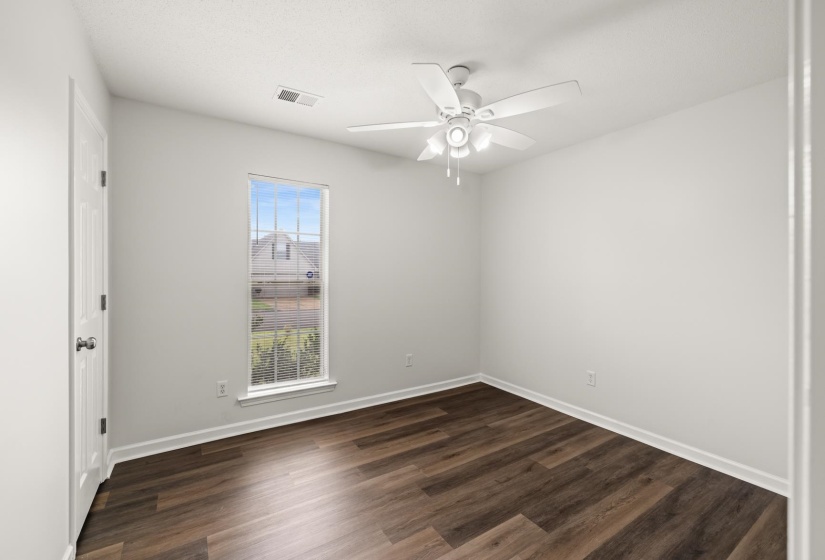 Light-filled room featuring wood-finish flooring, white baseboards, and a contemporary ceiling fan with integrated lighting