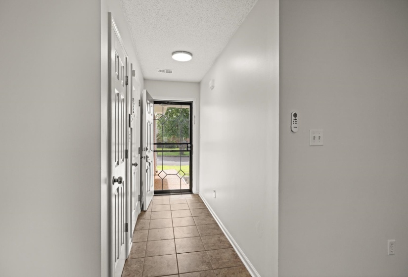 Entryway featuring ceramic tile flooring, paneled interior doors, and a security screen door with decorative grilles