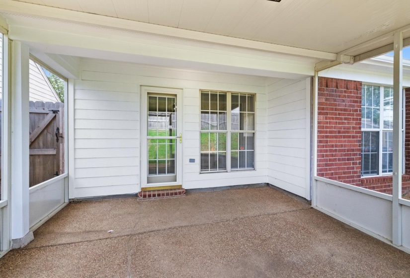 Covered patio featuring a textured concrete surface, white siding, and brick exterior elements