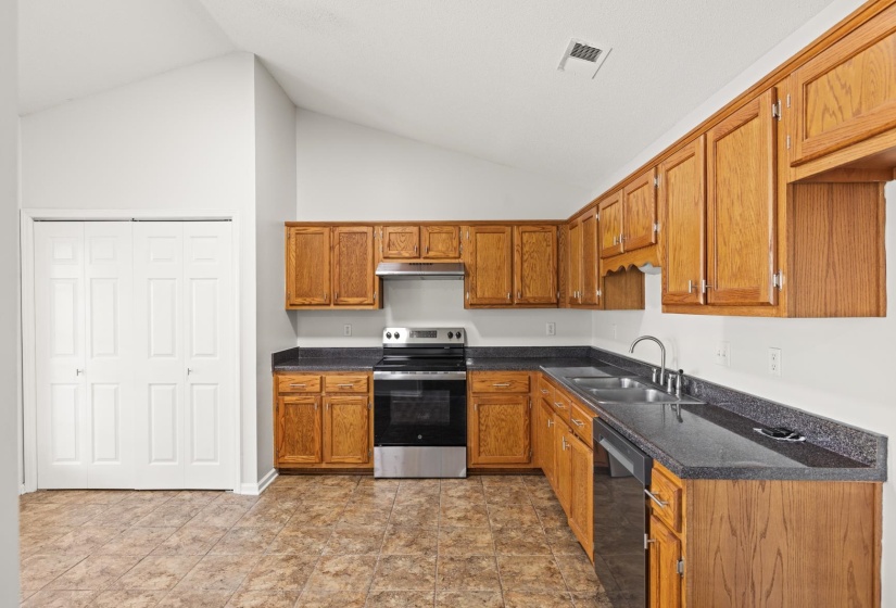 Kitchen featuring wood cabinetry, dark countertops, a stainless steel range, and a double basin sink