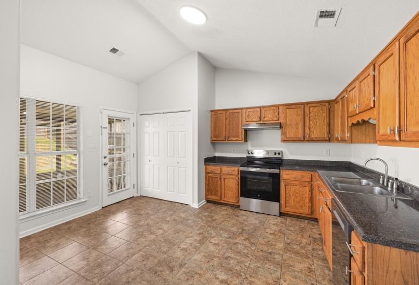 Kitchen with wood cabinetry, dark countertops, and stainless steel appliances