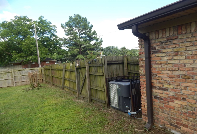 Brick exterior with dark brown gutters and an enclosed HVAC unit