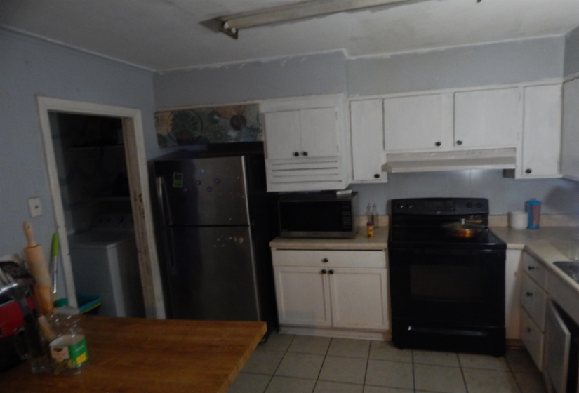 Kitchen featuring white cabinetry, a black electric range, and a stainless steel refrigerator