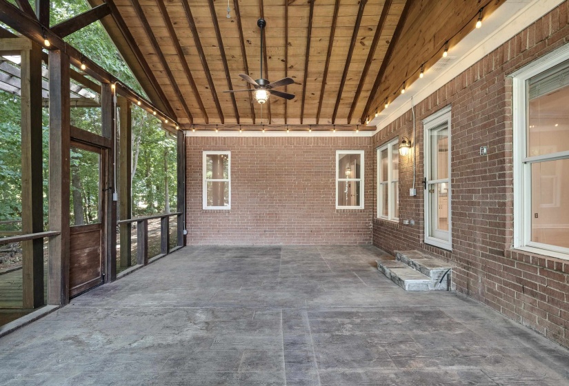 Spacious screened porch featuring a brick exterior wall, a wood-plank ceiling, and a ceiling fan