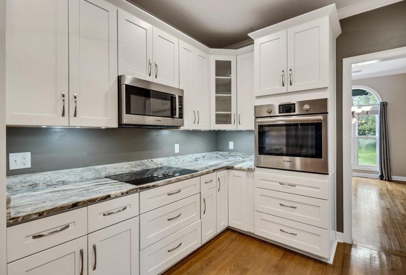 Modern kitchen featuring white shaker cabinetry, stainless steel appliances, a built-in wall oven, an integrated cooktop, and stone countertops