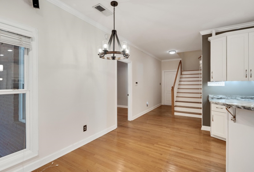Open-concept room featuring light wood-finish flooring, white walls, and crown molding