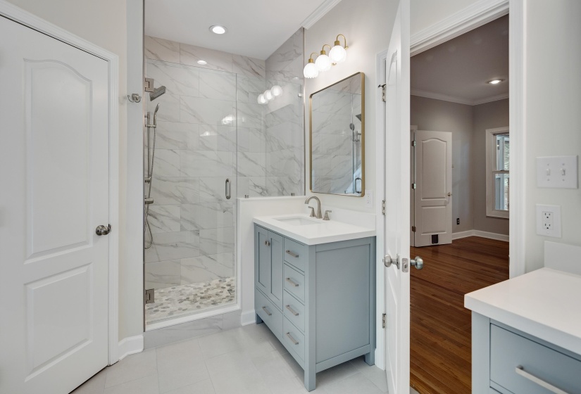 Bathroom featuring a glass-enclosed shower with large format tile surround and pebble tile flooring